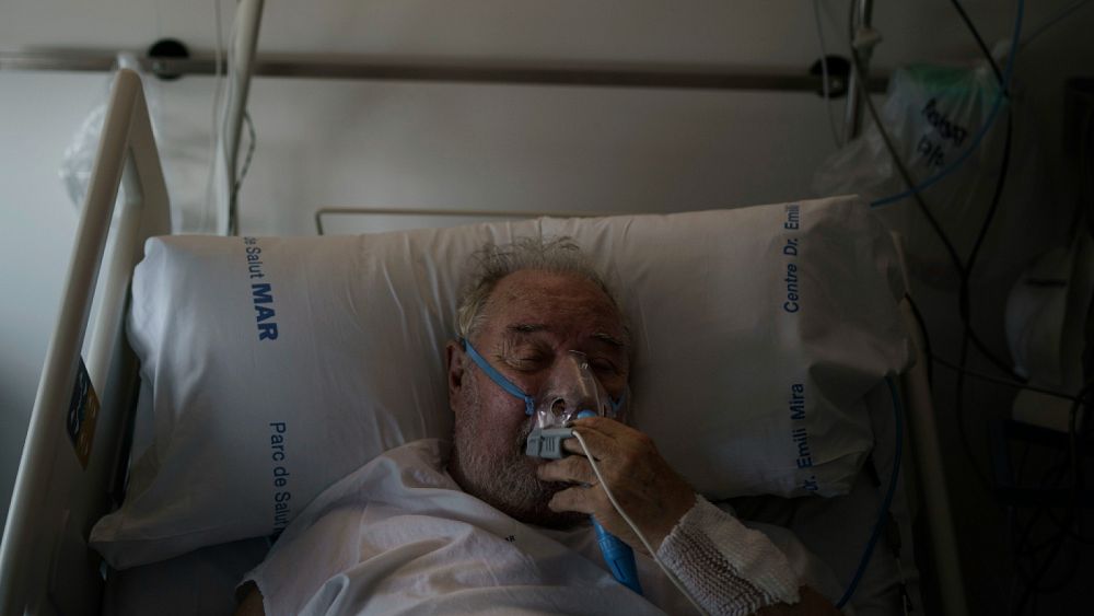 Пациент с COVID 19 настройва кислородната си маска докато получава лечение