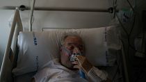 A COVID-19 patient adjusts his oxygen mask as he receives treatment in the Hospital del Mar in Barcelona, Spain, 2021.