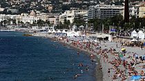 Peu de neige : Les gens bronzent et se baignent sur la longue plage de galets de Carras dans le centre de Nice sur la Côte d'Azur.