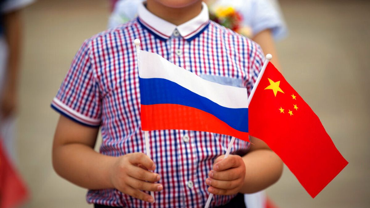 FILE - A boy holds Russian and Chinese flags before a welcoming ceremony for Russian President Vladimir Putin at the Great Hall of the People in Beijing on June 25, 2016.