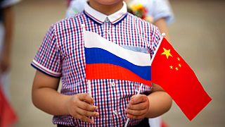 FILE - A boy holds Russian and Chinese flags before a welcoming ceremony for Russian President Vladimir Putin at the Great Hall of the People in Beijing on June 25, 2016.