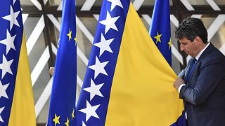 A member of protocol adjusts the Bosnia- Herzegovina flag prior to arrivals at an EU summit in Brussels, Thursday, June 23, 2022. 
