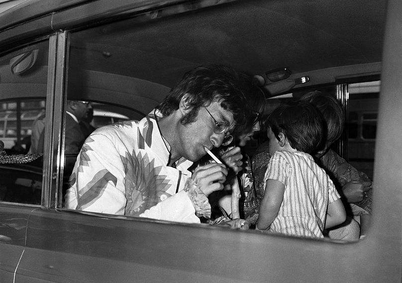 John Lennon from The Beatles lights a cigarette on his arrival at Heathrow Airport in London, England from Athens, Greece on July 31, 1967.