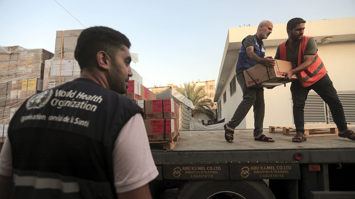 فلسطينيون يفرغون صناديق أدوية من شاحنة وصلت إلى مجمع ناصر الطبي