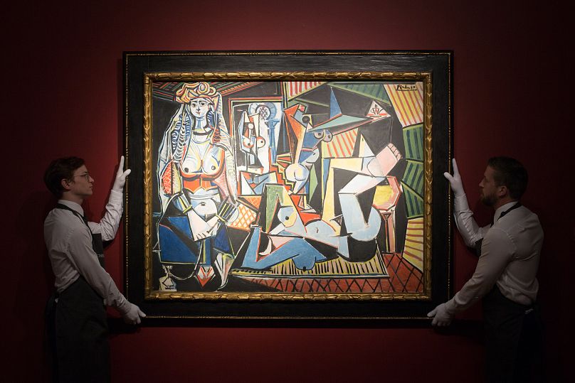 Christie's employees pose for pictures with a painting by Pablo Picasso called 'Les femmes d'Alger (Version "O")' at the auction house in London, Friday, April 10, 2015.