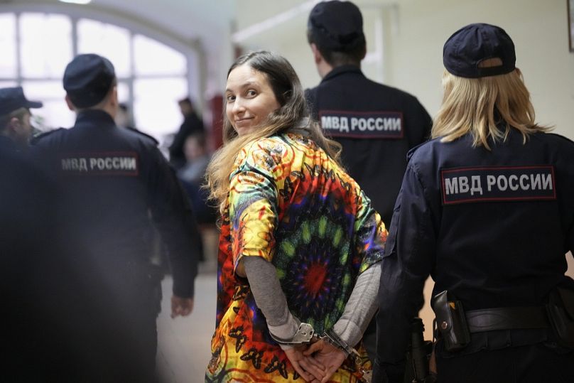 FILE - Sasha Skochilenko, a 33-year-old artist and musician, walks escorted by officers to the court room for a hearing in the Vasileostrovsky district court in St. Petersburg