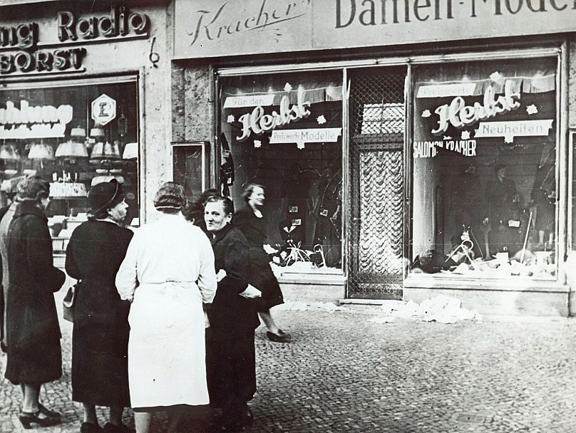 Nazi Almanyası'nda 9 Kasım 1938'de Yahudilere karşı toplu saldırıların başladığı "Pogrom Gecesi"nde tahrip edilen bir Yahudi esnafa ait dükkanın önünde bekleyenler (arşiv)