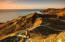 Man standing on coastal path with view of path ahead in Folkestone, Kent