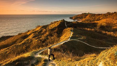 Man standing on coastal path with view of path ahead in Folkestone, Kent