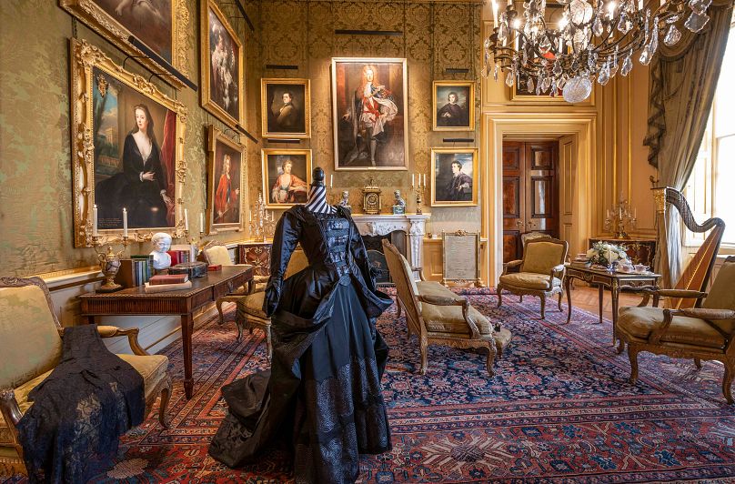 A room inside Blenheim Palace, sumptuously decorated, and with a black dress on display on a mannequin. Blenheim Palace