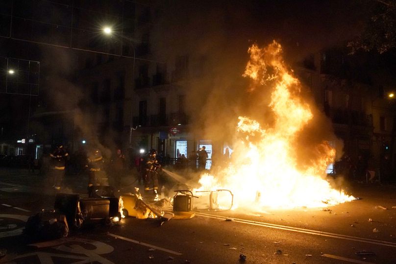 Vigili del fuoco spengono contenitori in fiamme durante una manifestazione contro l'amnistia presso la sede del partito socialista a Madrid, Spagna, 9 novembre 2023