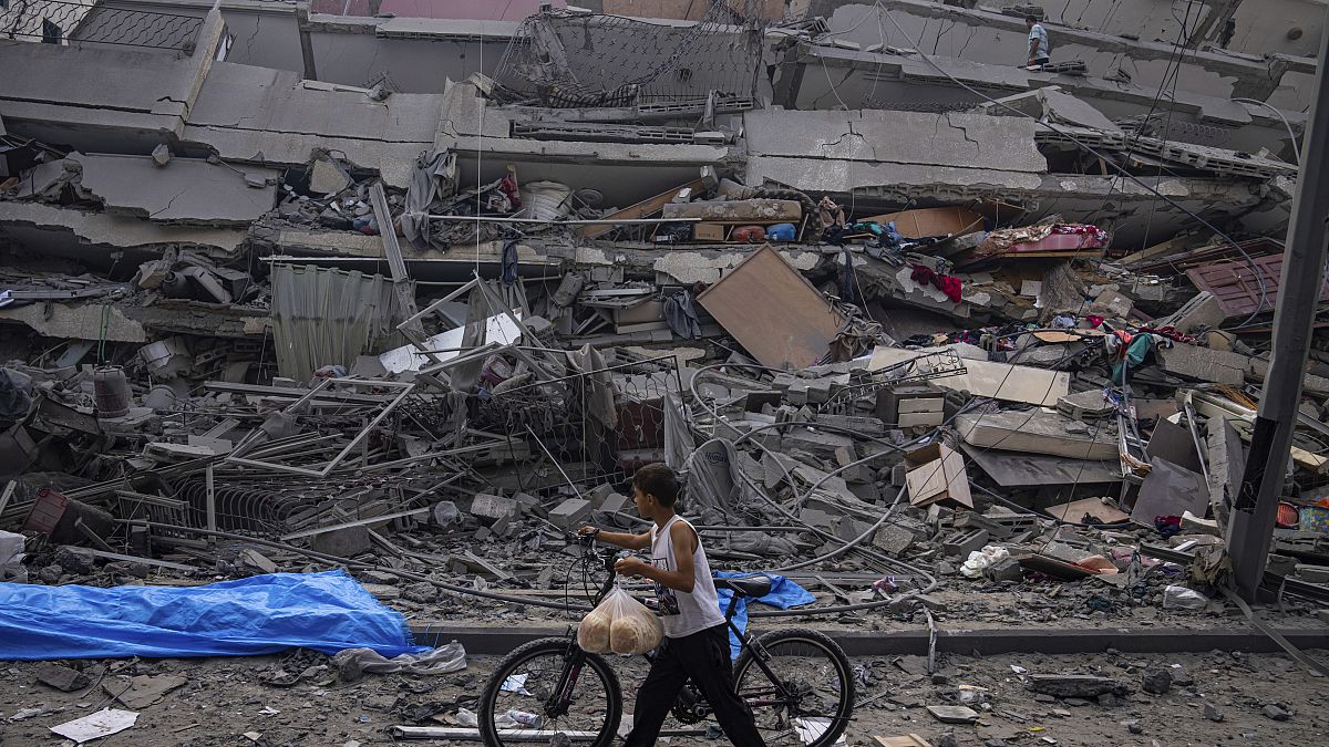 Un enfant palestinien marche avec son vélo près des décombres d'un bâtiment touché par une frappe aérienne israélienne, dans la ville de Gaza, dimanche 8 octobre 2023.
