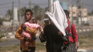فلسطيني وزوجته على طريق النزوح من شمال غزة باتجاه الجنوب ورفع راية بيضاء اتقاء للقصف الإسرائيلي  