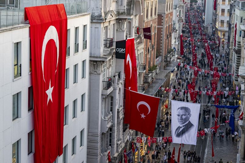 Turkish national flags and a banner depicting Mustafa Kemal Ataturk, the founding father of the Republic of Turkey, are displayed on Istiklal Avenue in Istanbul, October 2023
