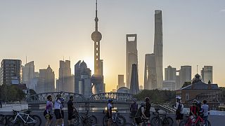 Cyclists, some take selfie as they take rest against the sunrise skylines in Pudong, China's financial and commercial hub, in Shanghai, China on Friday, Nov. 3, 2023.