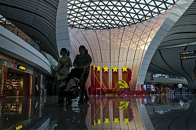 Travellers walk by a Communist Party's logo decorated at the departure hall of Beijing Daxing International Airport, in Beijing on Oct. 24, 2023.