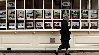 A woman walk past an estate agents in the Hampstead area of north London, Thursday, Oct. 7, 2010.