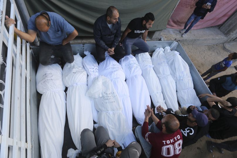 A pénteki bombázásokban meghalt Hidzsazi-család tagjainak holttestei mellett ülnek palesztinok