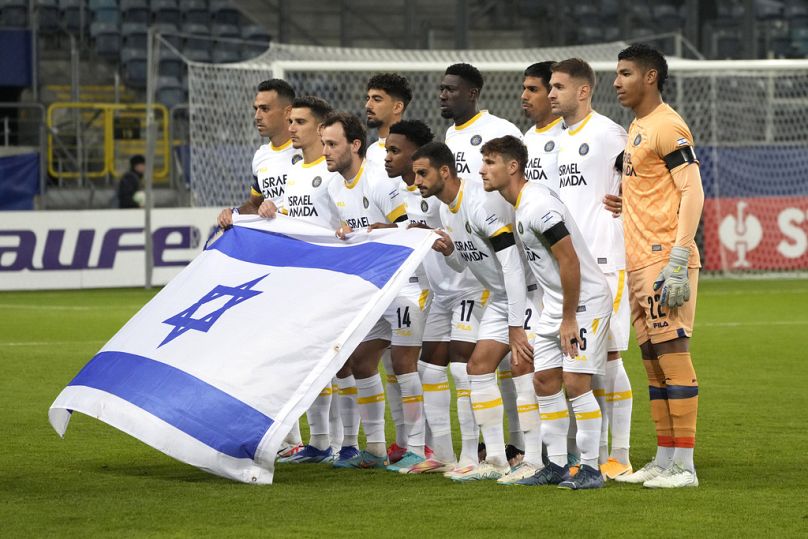 Maccabi Tel Aviv players show an Israeli flag as they pose for the official photo before the Europa Conference League group B soccer match between Zorya Luhansk and Maccabi Te