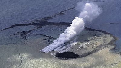 A new island, 100 meters in diameter, formed by erupted rock, is seen near the steam, according to Kyodo News. 