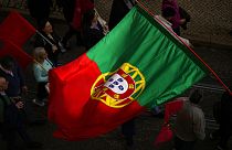 A Portuguese flag is carried among people in Lisbon protesting the rising cost of living, Thursday, Feb. 9, 2023. 