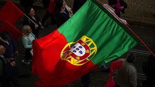 A Portuguese flag is carried among people in Lisbon protesting the rising cost of living, Thursday, Feb. 9, 2023. 