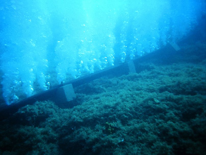 A large, perforated hose laid on the seabed blows bubbles to the surface, creating a noise barrier.