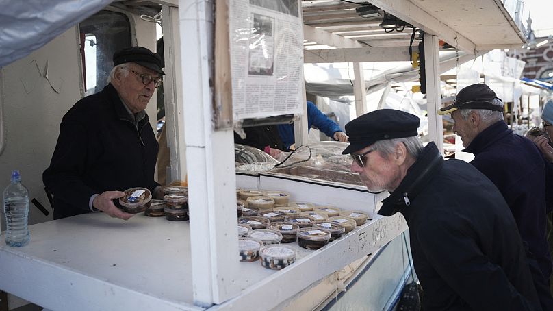 Herring fisherman Holger Sjogren (L) sells herring products on his boat at the fish market in Helsinki, Finland on October 6, 2023.