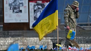 A serviceman mourns next to a Ukrainian flag at a makeshift memorial for fallen soldiers at Independence Square in Kyiv