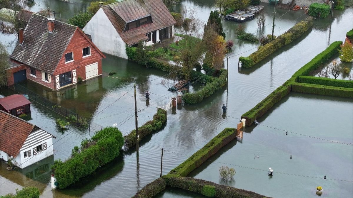 This aerial photograph taken on November 10, 2023 shows pedestrians walking in a flooded road in La Calotterie, northern France. 