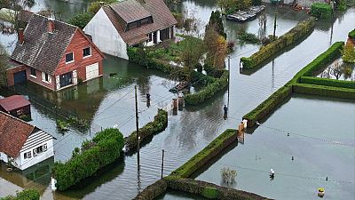 This aerial photograph taken on November 10, 2023 shows pedestrians walking in a flooded road in La Calotterie, northern France. 