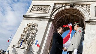 French President Emmanuel Macron shakes hands with FMilitary Governor of Paris and Army Corps General Christophe Abad (R) after a ceremony at the Tomb of the Unknown Soldier