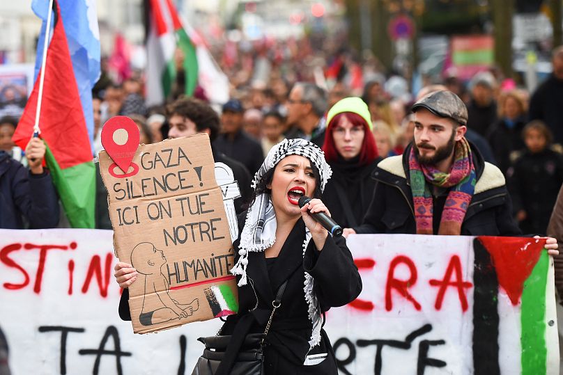 Манифестантка с плакатом "В Газе - под наше молчание - убивают человечность" на парижской акции в поддержку Палестины, 11 ноября 2023 г.