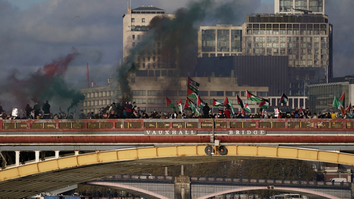 Protesters wave flags and hold flares during a pro-Palestinian protest in London, Saturday, Nov. 11, 2023.