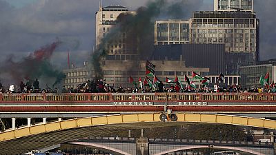 Protesters wave flags and hold flares during a pro-Palestinian protest in London, Saturday, Nov. 11, 2023.