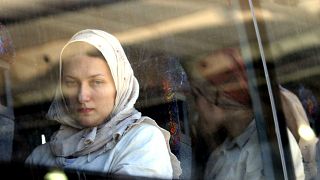 سيدة أوكرانية وعائلات أخرى تجلس على متن حافلة بعد عبور معبر إيريز من شمال قطاع غزة إلى إسرائيل. 