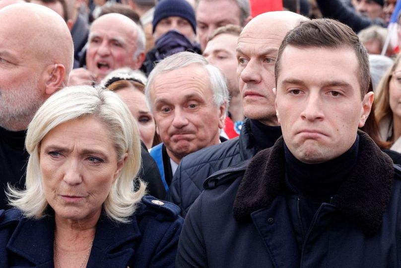 French far-right party Rassemblement National (RN) member of Parliament Marine Le Pen (L) and resident of French RN Jordan Bardella (R) attend the march