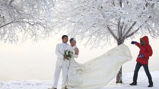 يلتقط زوجان صور زفاف بجانب الأشجار المغطاة بالجير على طول نهر سونغهوا في مدينة جيلين، مقاطعة جيلين شمال شرق الصين، يوم الاثنين 3 يناير 2011.