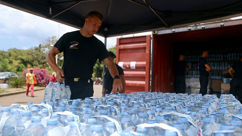 A security officer picks up water bottles for residents in Tsoundzou, on the French Indian Ocean territory of Mayotte, 21 October2023.