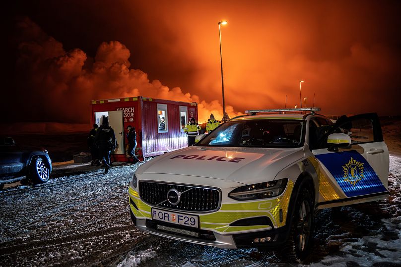 Un véhicule de police garé à l'entrée de la route de Grindavík, avec l'éruption en arrière-plan, le 18 décembre 2023.