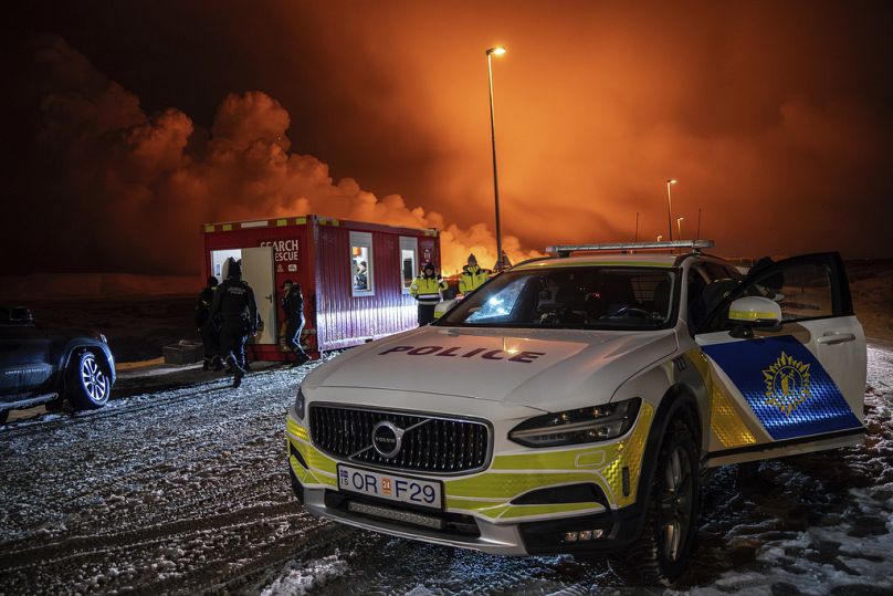 El vehículo policial está aparcado a la entrada de la carretera de Grindavík con la erupción al fondo