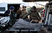 Des policiers remettent un homme blessé à des employés du service d'urgence ukrainien sur une route à l'extérieur d'Avdiivka, dans la région de Donetsk, le 13 novembre 2023