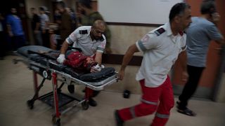مسعفون فلسطينيون ينقلون طفلا مصابا للعلاج في مستشفى دير البلح إثر قصف إسرائيلي