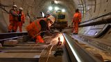 Construction workers work on a section of train track inside a Crossrail tunnel, beneath Stepney in east London on November 16, 2016. 