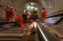 Construction workers work on a section of train track inside a Crossrail tunnel, beneath Stepney in east London on November 16, 2016. 