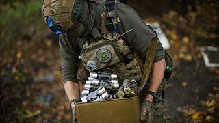 A Ukrainian territorial defence deminer takes Russian ammunition left behind as his team clears mines near Hrakove village, Ukraine, Oct. 13, 2022.