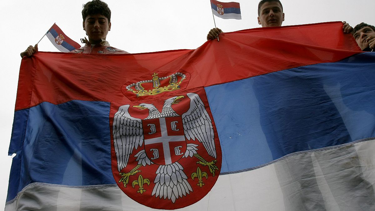 Молодые сербы держат флаг Сербии в Косове