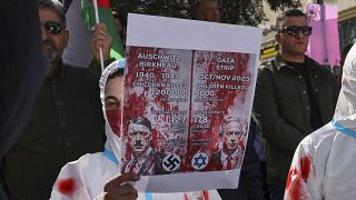 متظاهر يرتدي كفنًا رمزيًا يرفع لافتة خلال مسيرة لدعم غزة والسجناء الفلسطينيين في السجون الإسرائيلية وسط مدينة الخليل بالضفة الغربية