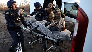 Polizisten übergeben einen Verwundeten an Mitarbeiter des ukrainischen Rettungsdienstes außerhalb von Awdijiwka (13. November 2023)
