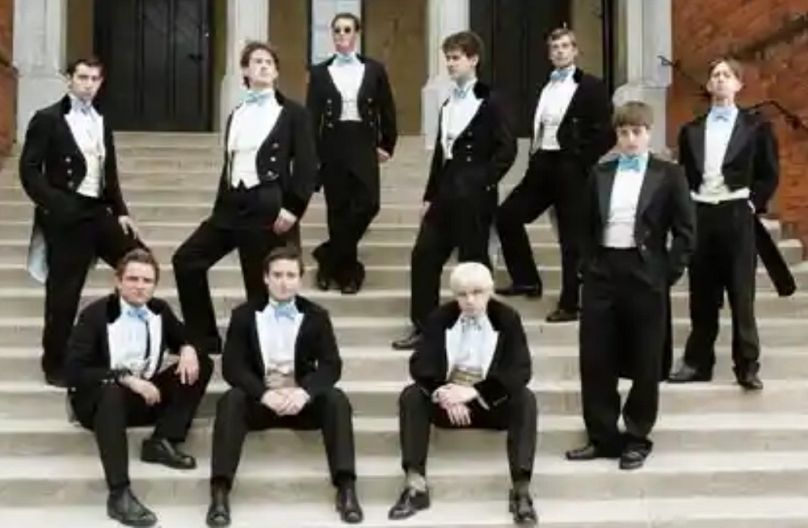 A Bullingdon Club tagjai, színészek által megjelenítve egy dokumentumfilmben: David Cameron balra fent a második, az alsó sorban a szőke pedig Boris Johnson